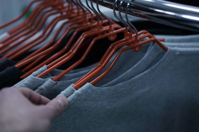 Cropped hand of woman holding clothes in shop