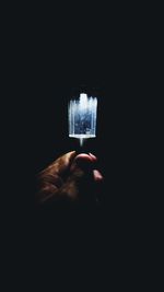 Close-up of hand holding lit candle in darkroom