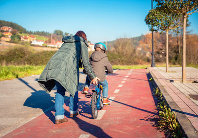 Rear view of people riding motorcycle on road