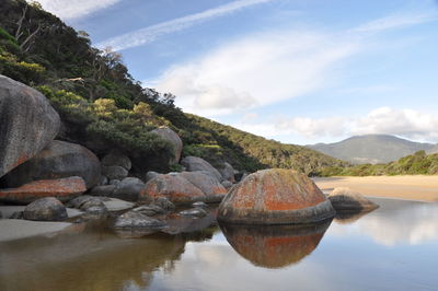 Rocks by lake against sky