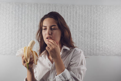 Woman eating banana at home