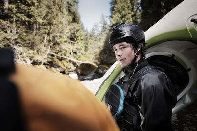 Kayaker looking at friend while standing in forest