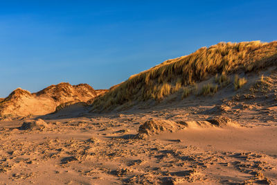 Scenic view of desert against clear blue sky