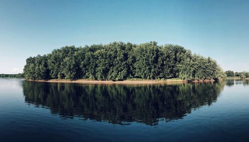 Reflection of trees in lake against clear sky