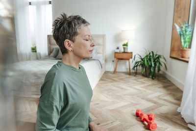 Woman doing meditation with eyes closed at home