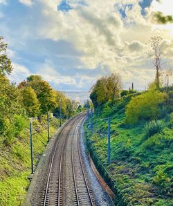 Railroad tracks along trees and plants against sky