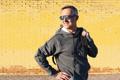 Man wearing sunglasses standing against brick wall