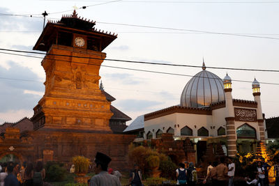 People outside temple against sky