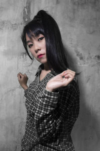 Portrait of a young woman standing against wall