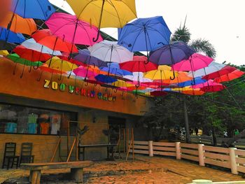 Low angle view of multi colored umbrellas hanging against sky