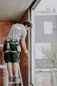 Rear view of man standing by window