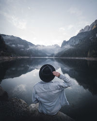 Rear view of man looking at lake against mountain range
