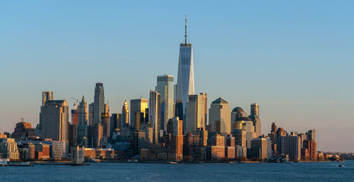 Sea by modern buildings against clear sky