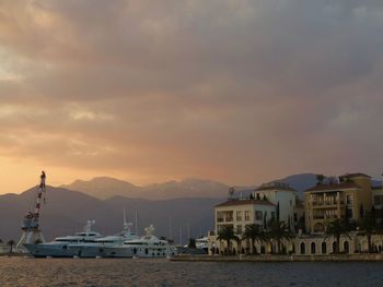 Boats moored at harbor against cloudy sky