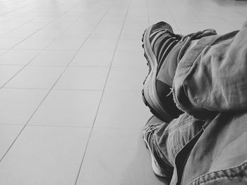Low section of man relaxing on tiled floor