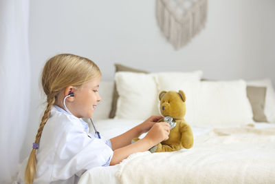 Woman holding toy while sitting on bed
