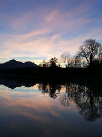 Silhouette trees by lake against sky during sunset