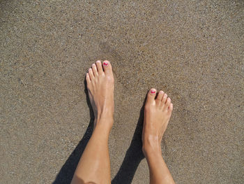Low section of woman legs on sand at beach