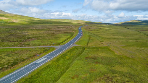 Scenic view of road amidst field against sky