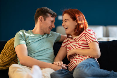 Side view of couple sitting on sofa at home