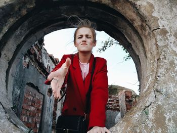 Portrait of woman gesturing through circle shape in wall