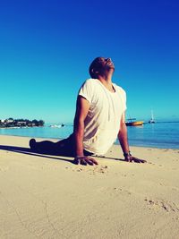 Full length of man exercising at beach against clear sky