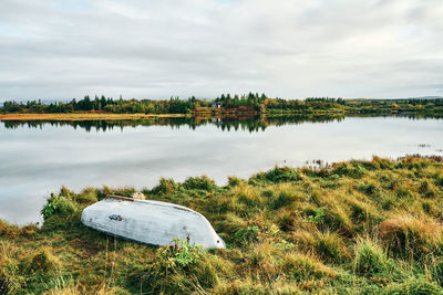 Landscape of lonely lake shore and overturned boat at countryside