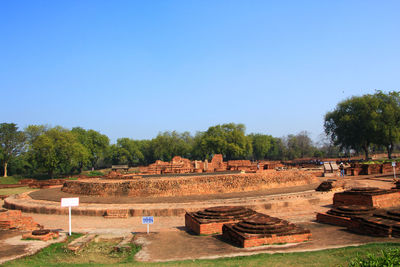 Built structure on landscape against clear blue sky