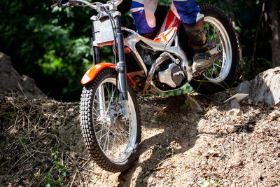 Low section of man riding motorcycle at forest