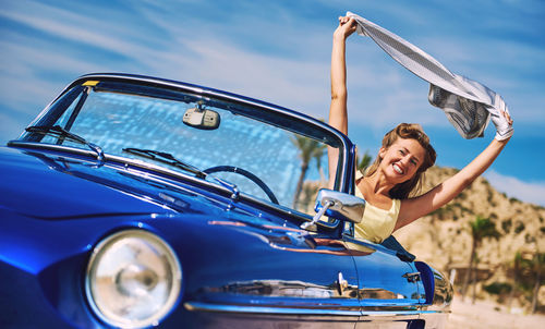 Smiling woman holding scarf aloft while sitting in car