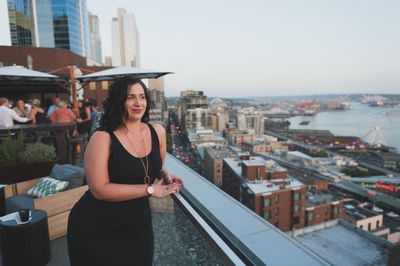 Young woman standing at terrace restaurant in city