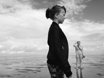 Female friends standing at beach against sky