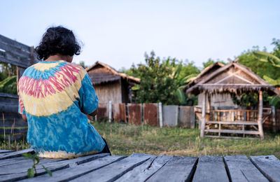 Rear view of woman sitting on boardwalk