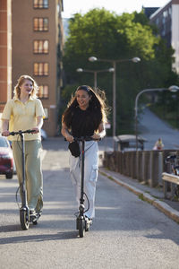 Young female friends riding electric push scooters