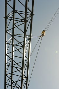 Low angel view of girder hanging by crane against sky