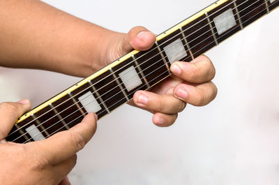 Cropped hands playing string instrument against white background