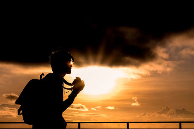Side view of woman standing against sky during sunset