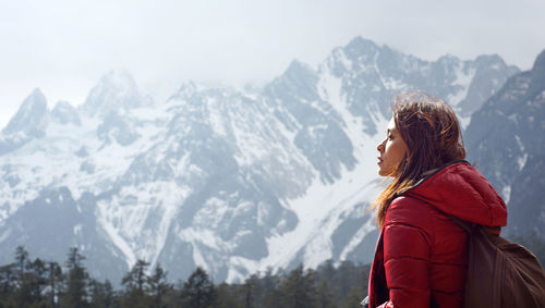 Side view of woman looking away against snowcapped mountains