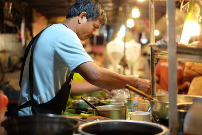 Side view of male vendor preparing food at night