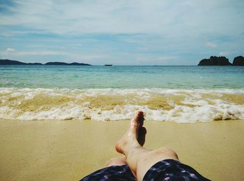 Low section of man relaxing on beach