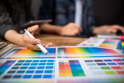 Close-up of hand holding colored pencils on table