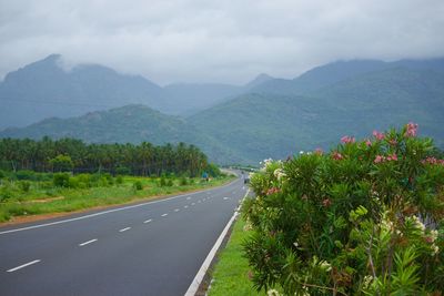 Scenic view of road by mountains against sky