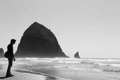 Full length of man standing at beach against clear sky