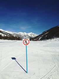 Road sign on snow covered mountain against sky