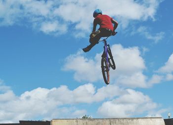 Low angle view of man jumping with bicycle against sky