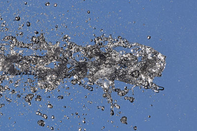 Low angle view of water drops on blue sky