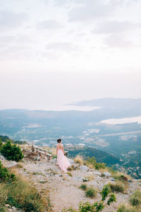 Rear view of woman sitting on landscape against sky