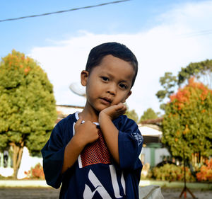 Portrait of young man standing against trees