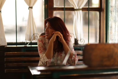 Woman looking away while sitting at table in restaurant