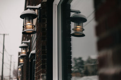 Electric lamps along side building with reflections in window.